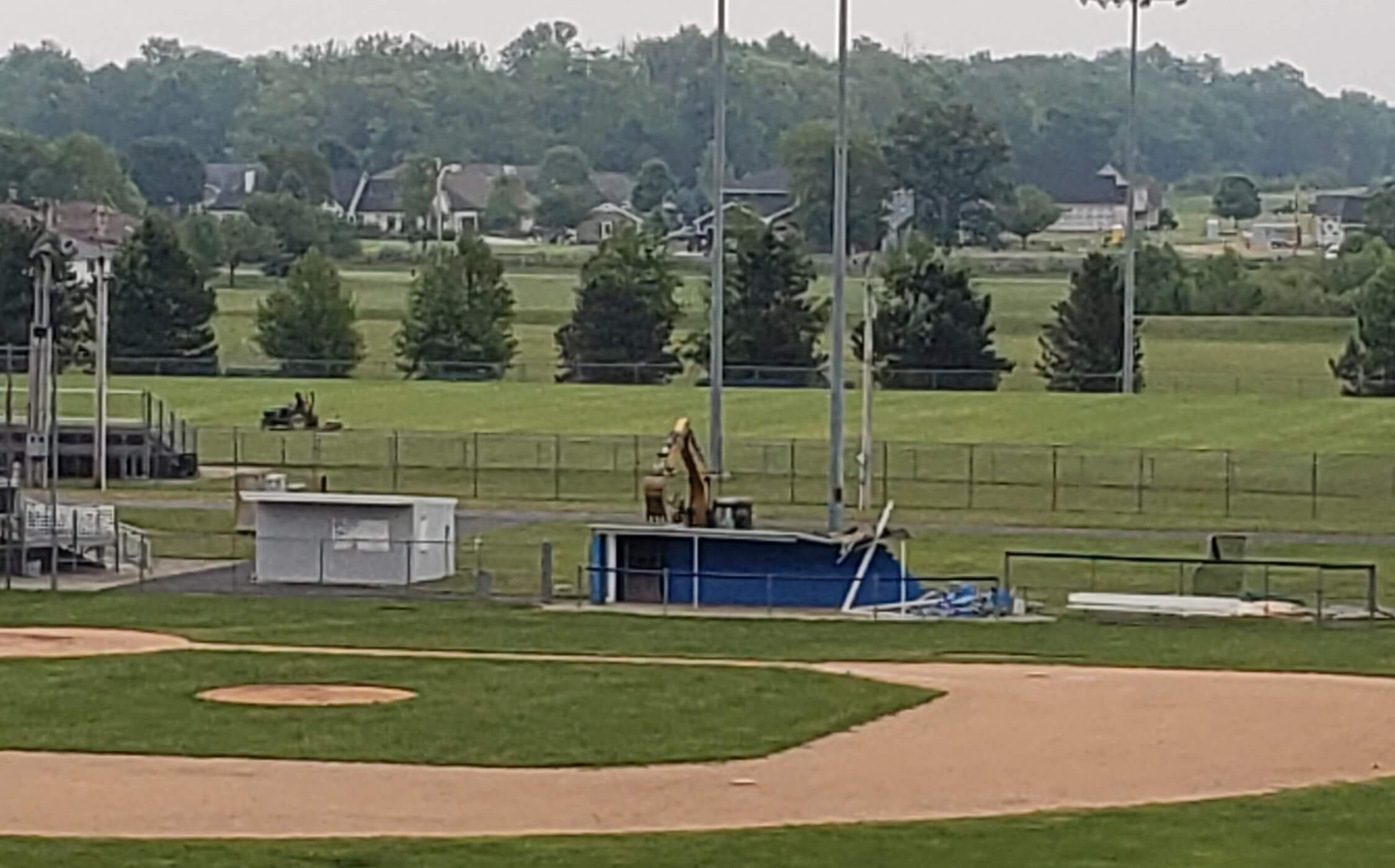An excavator tears into the roof of the old blue dugout.