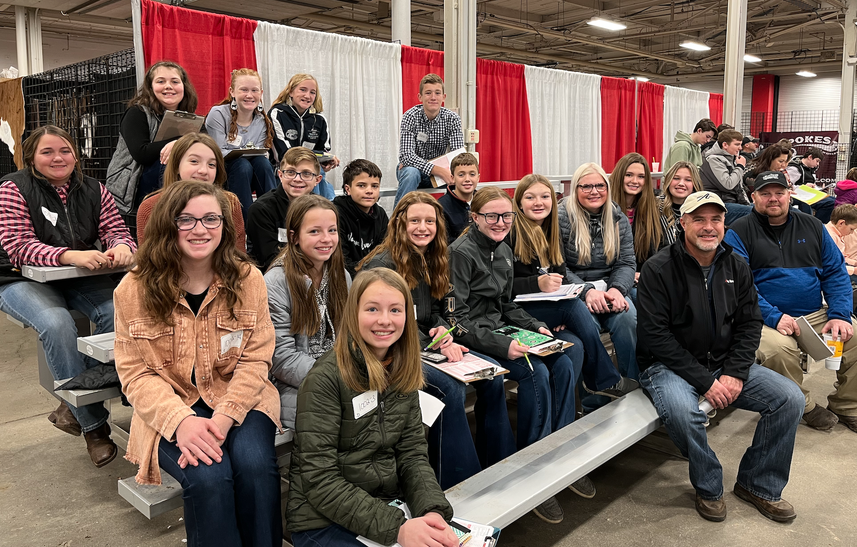 Tipton Livestock Judging Team is pictured at the contest. Members are seated on bleachers in front of a red and white cloth