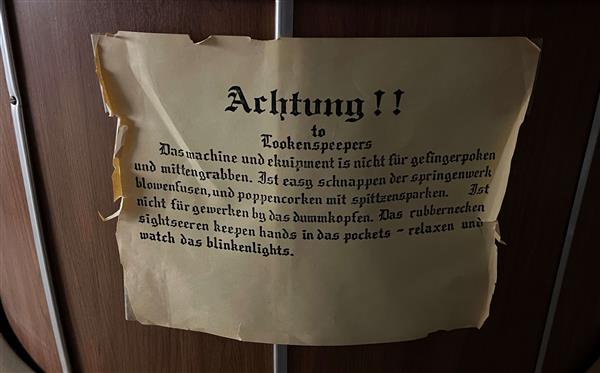 This is a sign that has been on the projector since its installation. It is written in faux German.