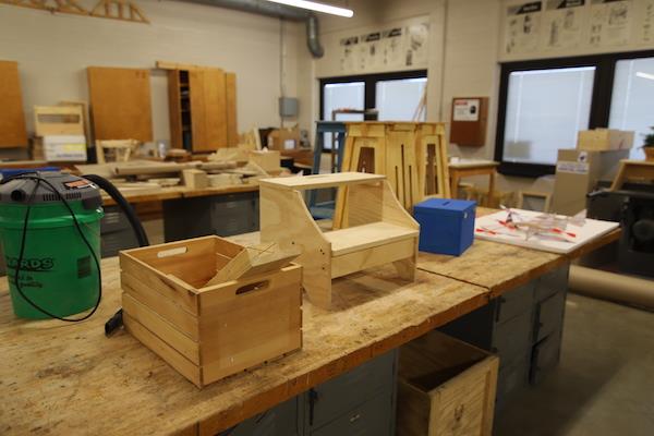 Several wooden items sit atop a long table. These items were made in the classroom.