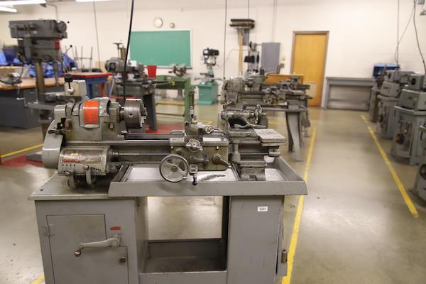 Machine in the metals lab. It has a small wheel near the middle and looks like it has a small drill head.