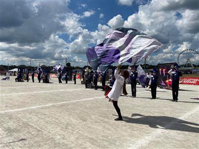 Member of the guard swings two purple and silver flags