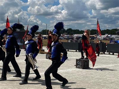 Several band members marching, each in step and wearing sharp black and blue uniforms
