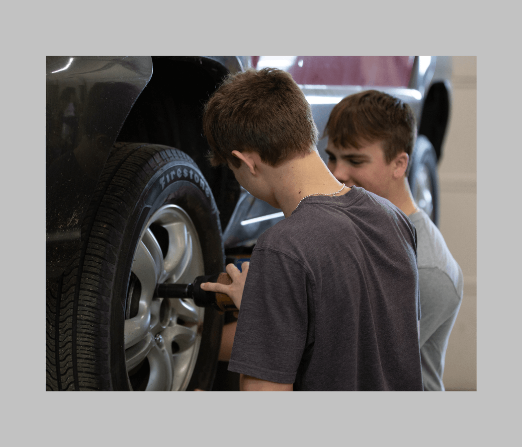two high school students work on a car